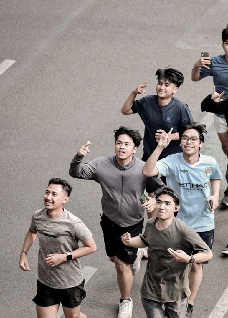 Anggota komunitas berlari bersama di jalan kota sambil tersenyum